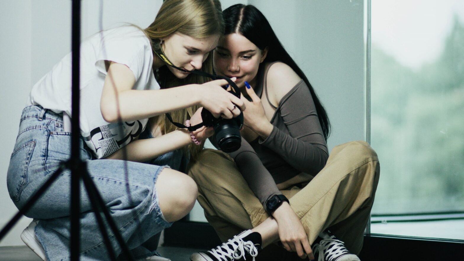 Dwie młode dziewczyny patrzą w wyświetlacz aparatu fotograficznego.