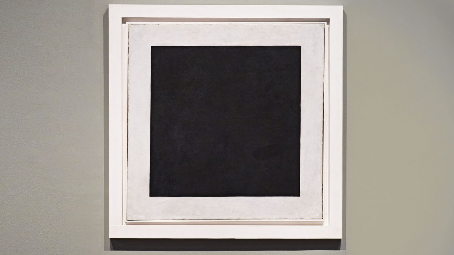 Wykonane w miejscu ekspozycji zdjęcie obrazu Kazimierza Malewicza Czarny kwadrat na białym tle. Płótno ma kształt kwadratu, w środku obrazu czarny kwadrat o lekko nierównych krawędziach, dookoła kwadratu białe tło. Rama ma również kolor biały. Ściana galerii ma delikatną fakturę, jest koloru beżowego.