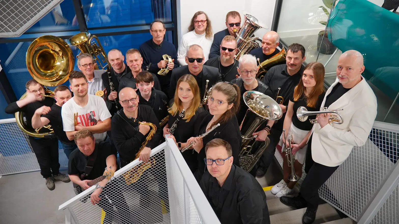Na zdjęciu grypa osób z Orkiestry WOAKu Vabank. Wszystkie osoby trzymają w ręku instrumenty, takie jak: puzon, trąbka, flet