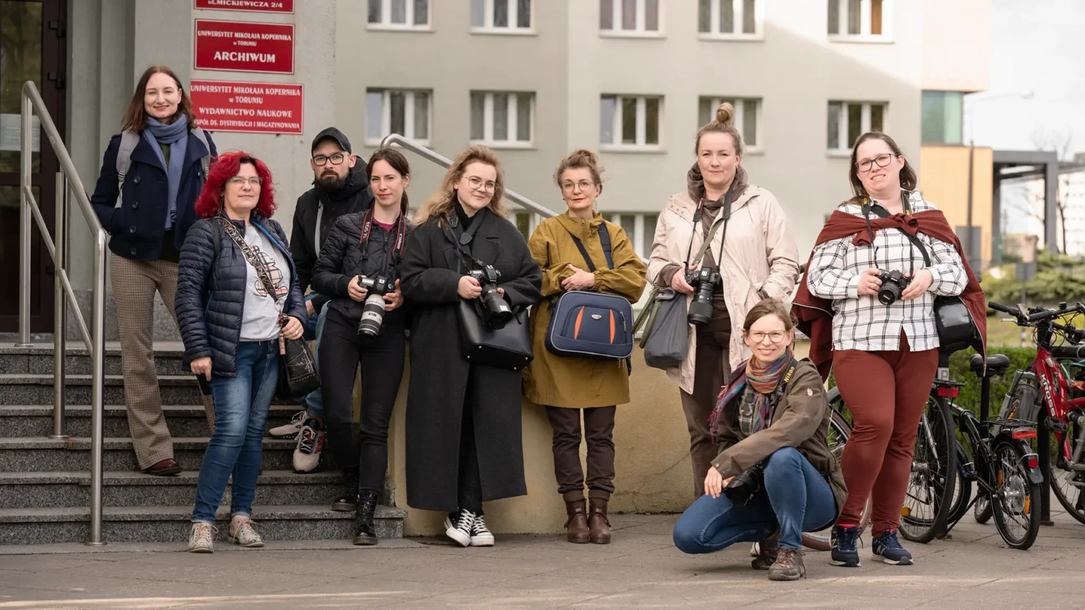 Na zdjęciu grupa osób pozująca do zdjęcia. Kilka z nich trzyma w rękach aparaty fotograficzne. Zdjęcie wykonał Jakub Fiszer.